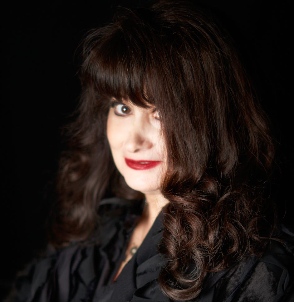 Portrait of a Susan Ottaviano in a black top against a black background.