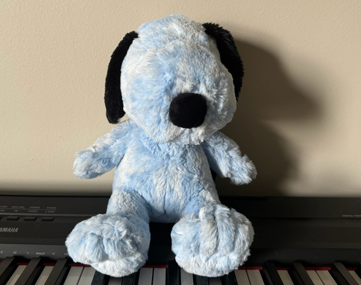 A Blue Snoopy stuffed toy sitting on top of a piano.