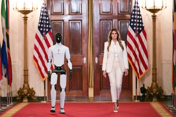 Melania Trump camina junto a un robot antropomórfico por un pasillo alfombrado de rojo, cuya entrada está flanqueada por dos banderas de Estados Unidos. Melania Trump camina junto a un robot antropomórfico por un pasillo alfombrado de rojo, cuya entrada está flanqueada por dos banderas de Estados Unidos.