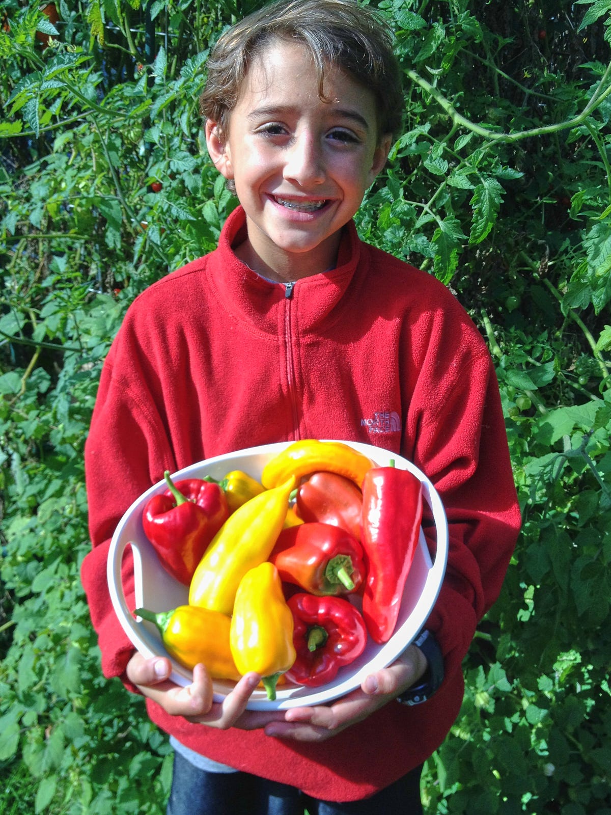 a boy holding a bowl of peppers