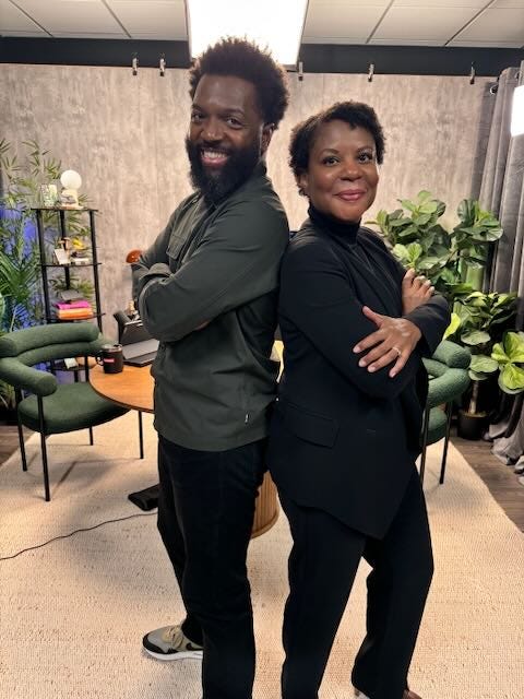 Baratunde standing back to back with Alondra. both with arms crossed looking cool AF in the Life With Machines studio