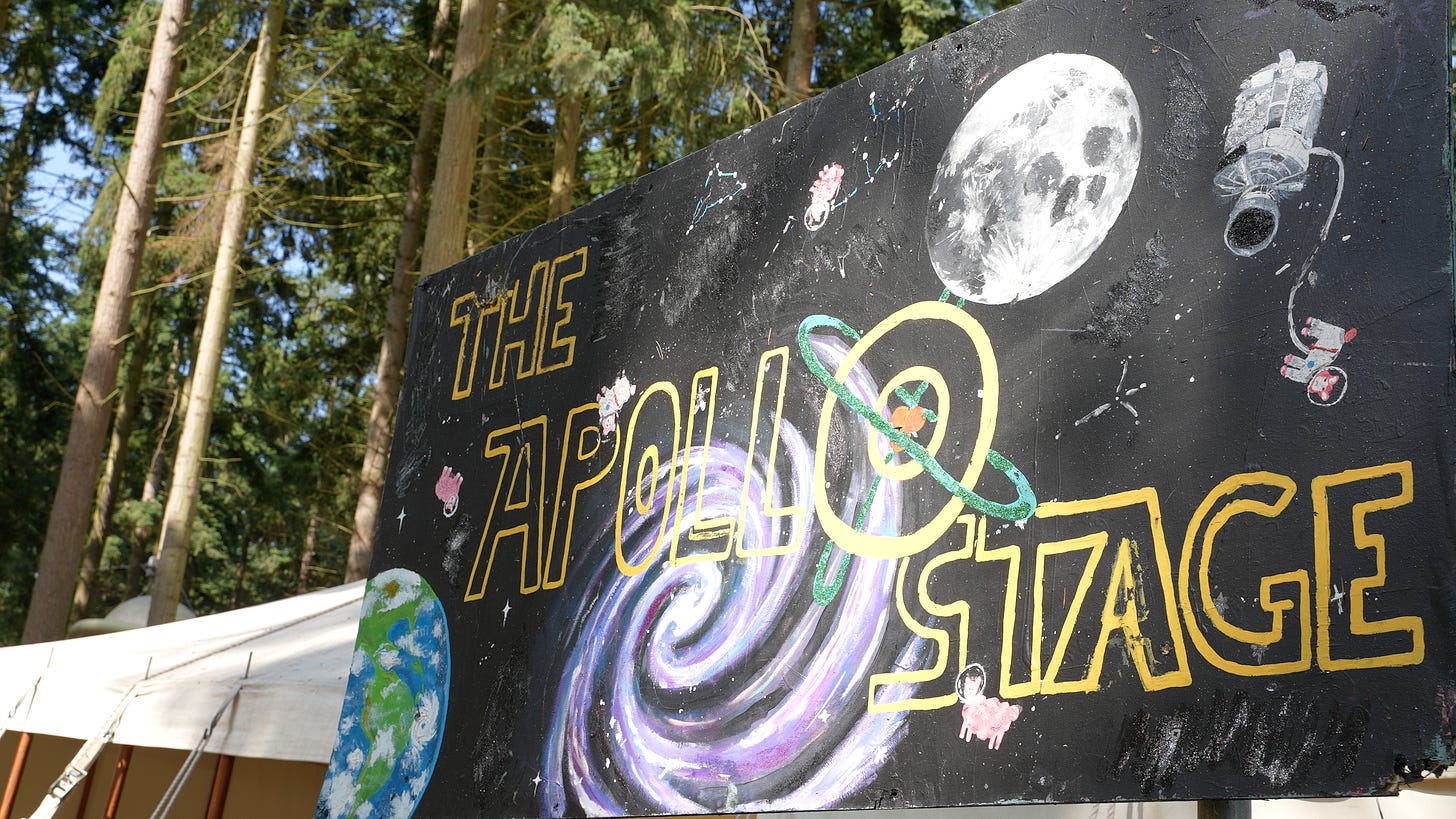 A painted sign that says The Apollo Stage. The artwork contains planets and satellites and some astronaut sheep.