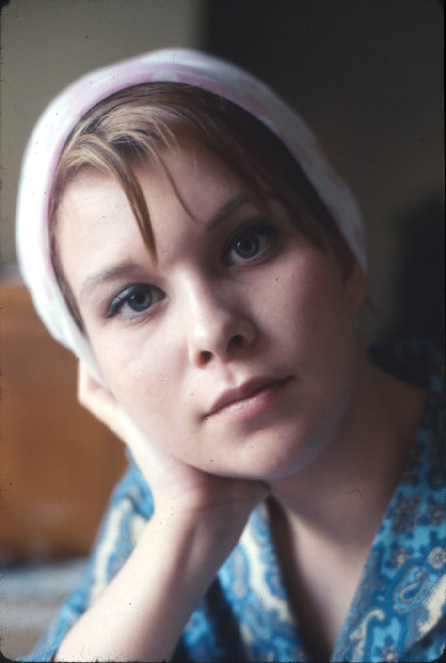 A close-up of my mother's face in 1967, when she was 21. She wears a pink head kerchief and stares contemplatively at the camera.