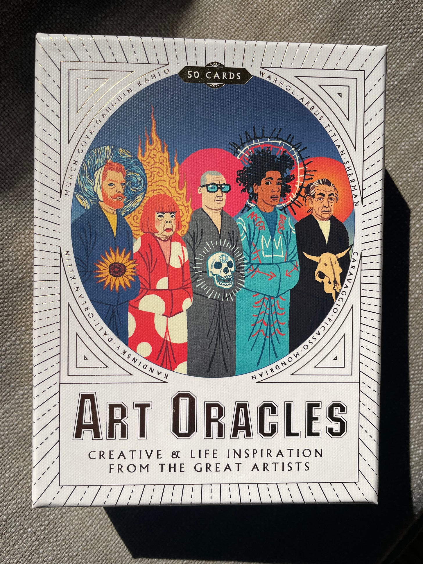 A white box, with gold lettering that reads, "Art Oracles: Creative and Life Inspiration from the Great Artists." In the center are knee-to-head portraits of five artists, including Basquiat, Van Gogh, and O'Keefe.