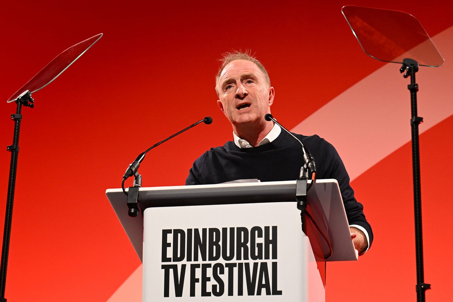 James Harding standing behind a lecture, giving a speech