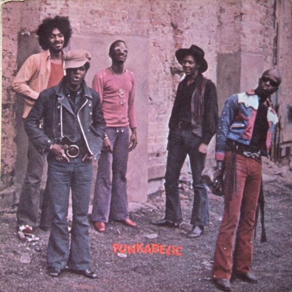 This may contain: four men standing in front of an old brick building with the word punkade written on it