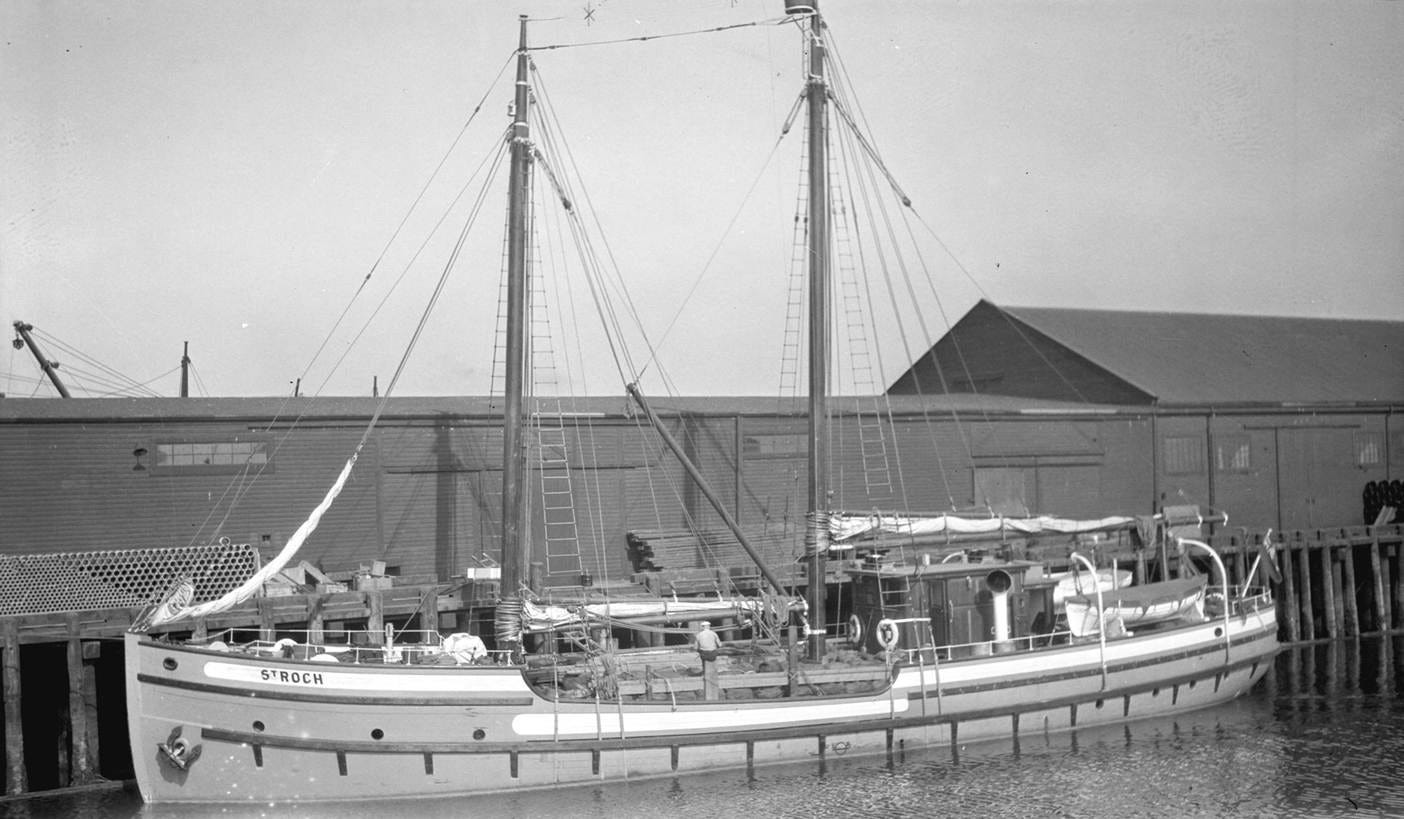 The image depicts an old, wooden sailboat docked at a maritime facility, with its masts and sails clearly visible, and the docking structure behind it.

AI-generated content may be incorrect.