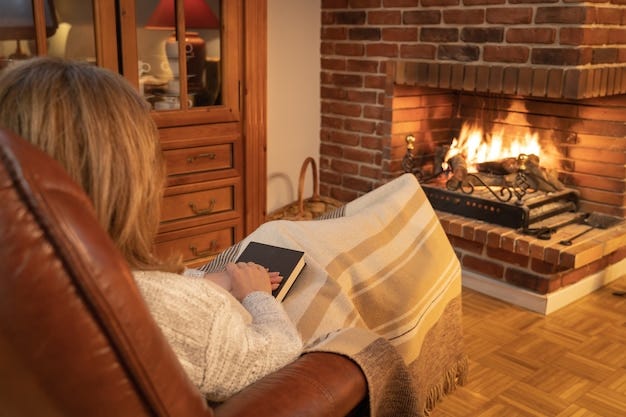 Woman resting in front of the fire in a fireplace in an armchair and  covered with a blanket. | Premium Photo