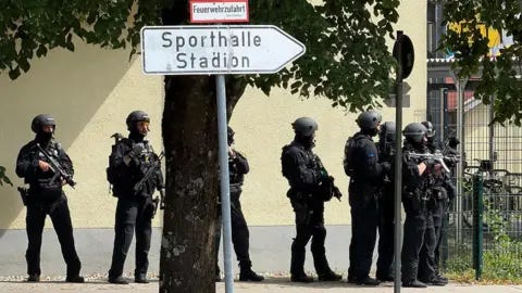 AFP via Getty Images Police officers stand with guns outside a school in Germany. AFP via Getty Images Police officers stand with guns outside a school in Germany.