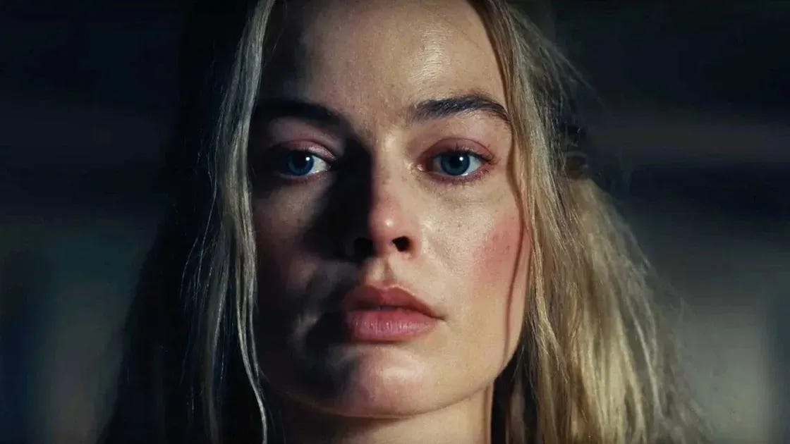 Beauty close-up of Margot Robbie showing a soft pink flush on the cheeks.