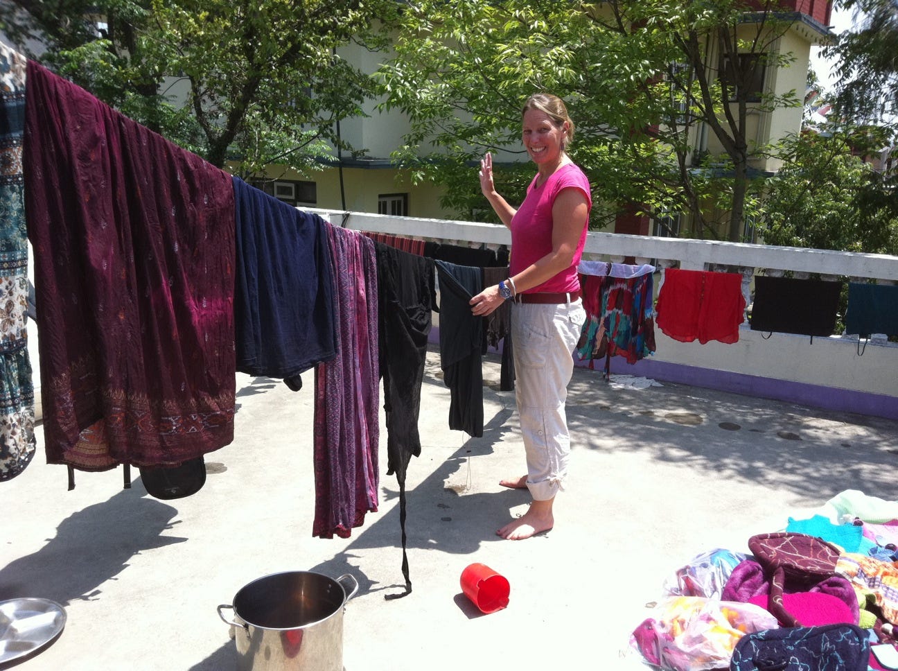 Blond woman hanging colorful laundry on sunny rooftop. 