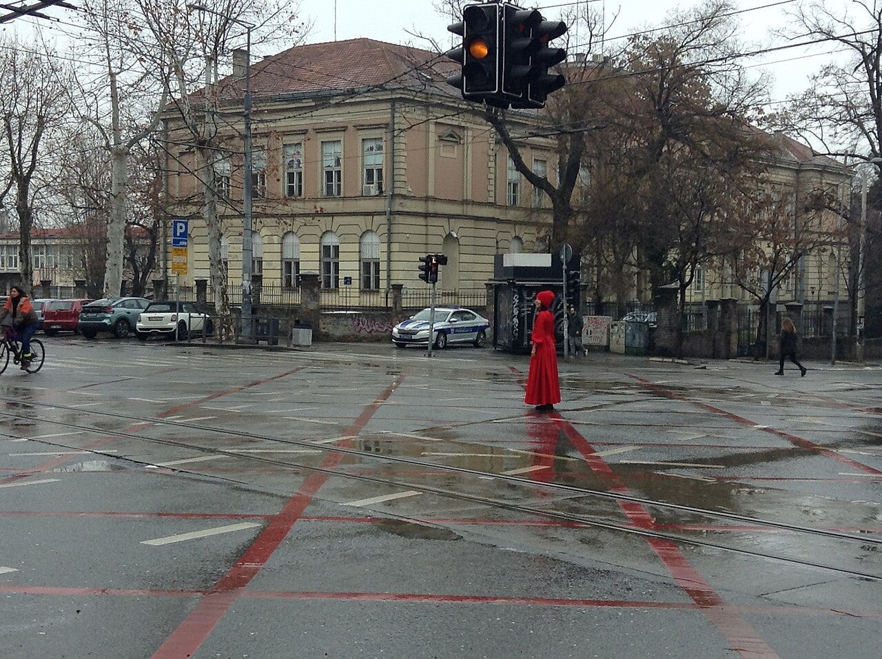 Una ragazza vestita di rosso ferma in mezzo a un incrocio di Belgrado Una ragazza vestita di rosso ferma in mezzo a un incrocio di Belgrado