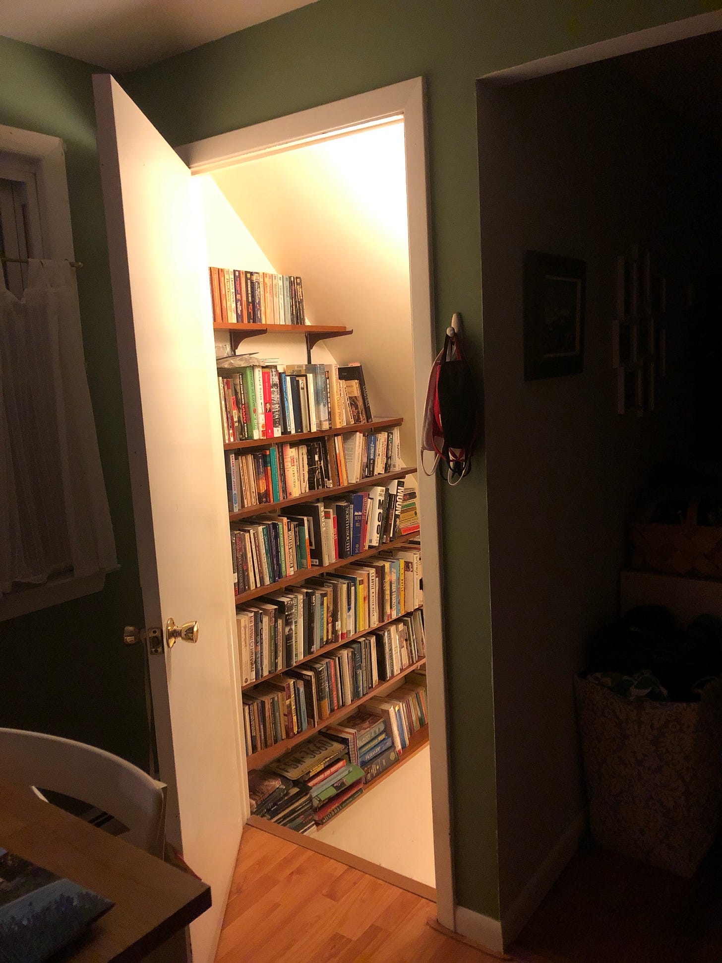 Open doorway into a lit stairwell lined with bookshelves