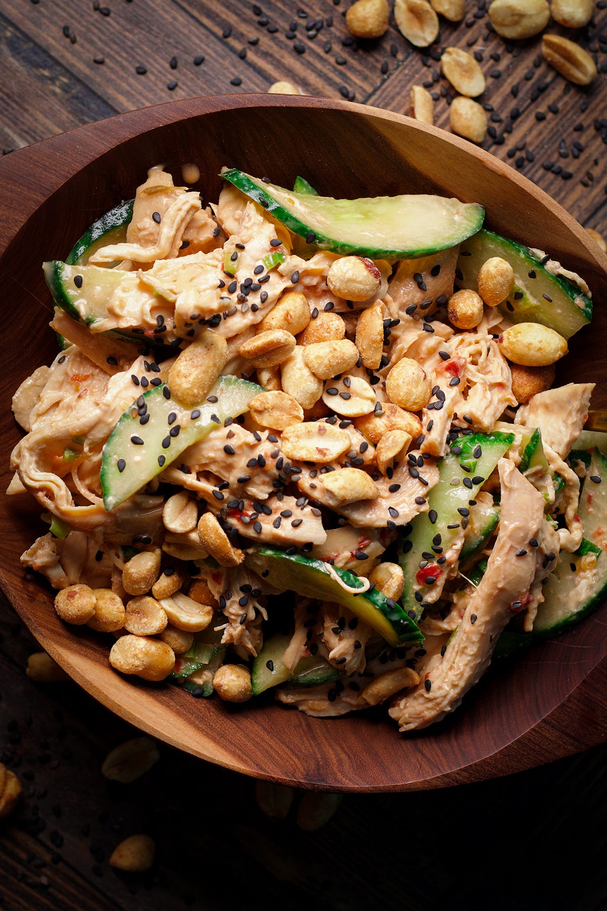 A bowl filled with sesame chicken salad with tahini dressing and roasted peanuts. A bowl filled with sesame chicken salad with tahini dressing and roasted peanuts.