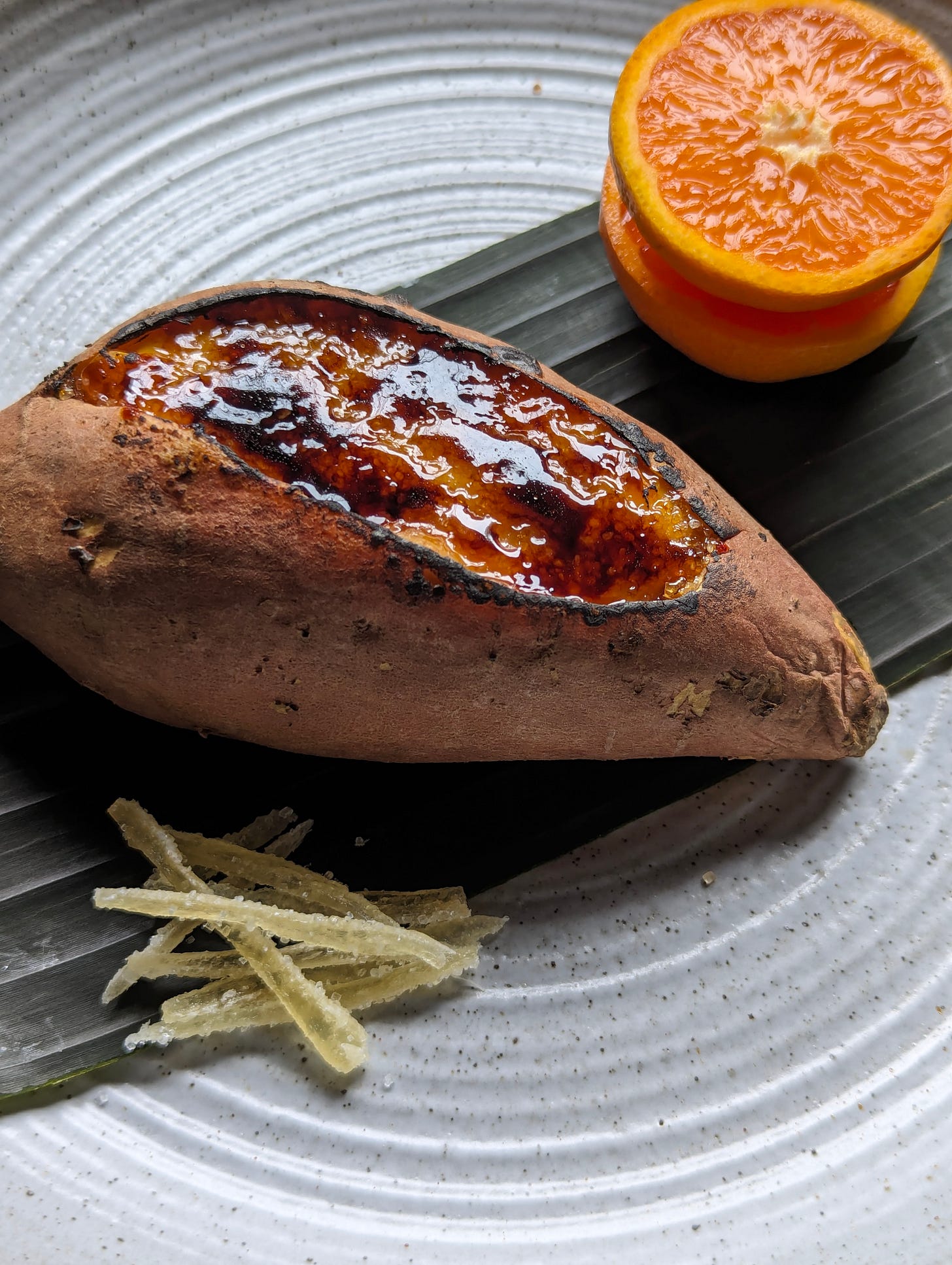 Plant-based Japanese Sweet Potato Crème Brûlée — topped with crackly caramelized sugar and served with mandarin slices and crystallized ginger.