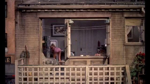 This may contain: two people are standing on the balcony of a small brick building with an open door