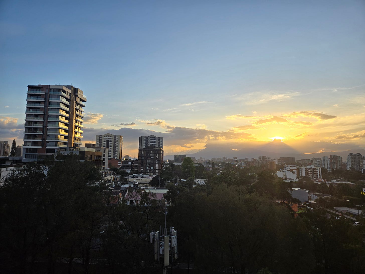 A view of the skyline of Guatemala City, with new high-rises in front of a volcano and the setting sun. A view of the skyline of Guatemala City, with new high-rises in front of a volcano and the setting sun.