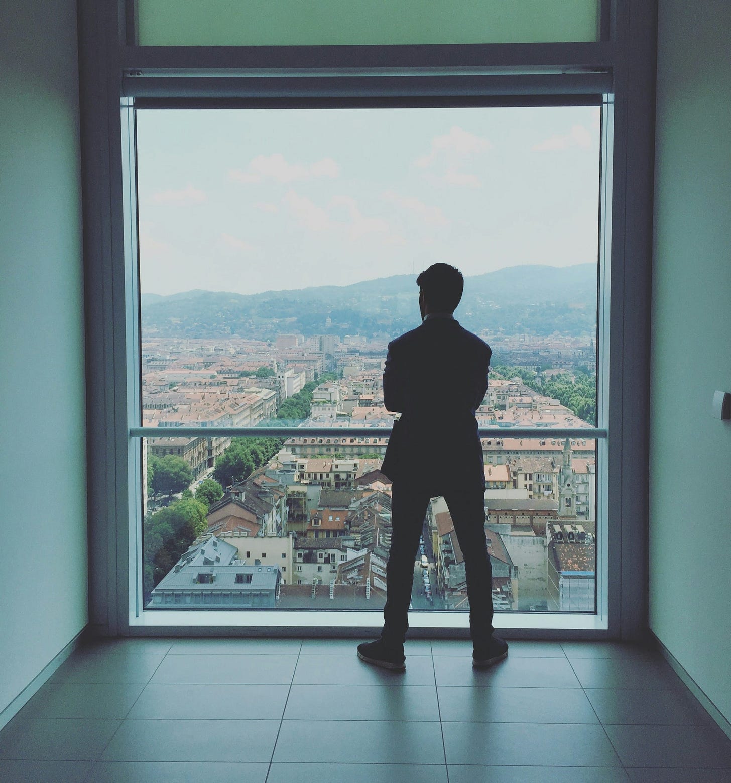 man standing near glass railing looking outside