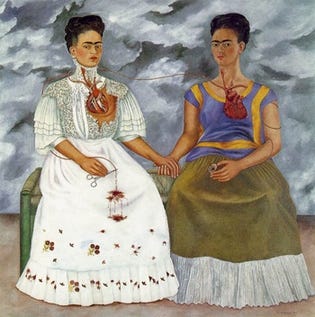 Two versions of Kahlo sit side by side on a bench holding hands under a stormy sky, one in a white lace dress and one in a Tehuana dress, their exposed hearts joined by a vein