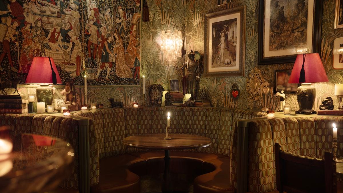 A booth with a round table in a restaurant whose walls are covered in art.