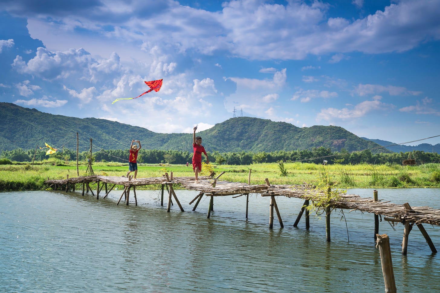 Childred running with kite on bridge