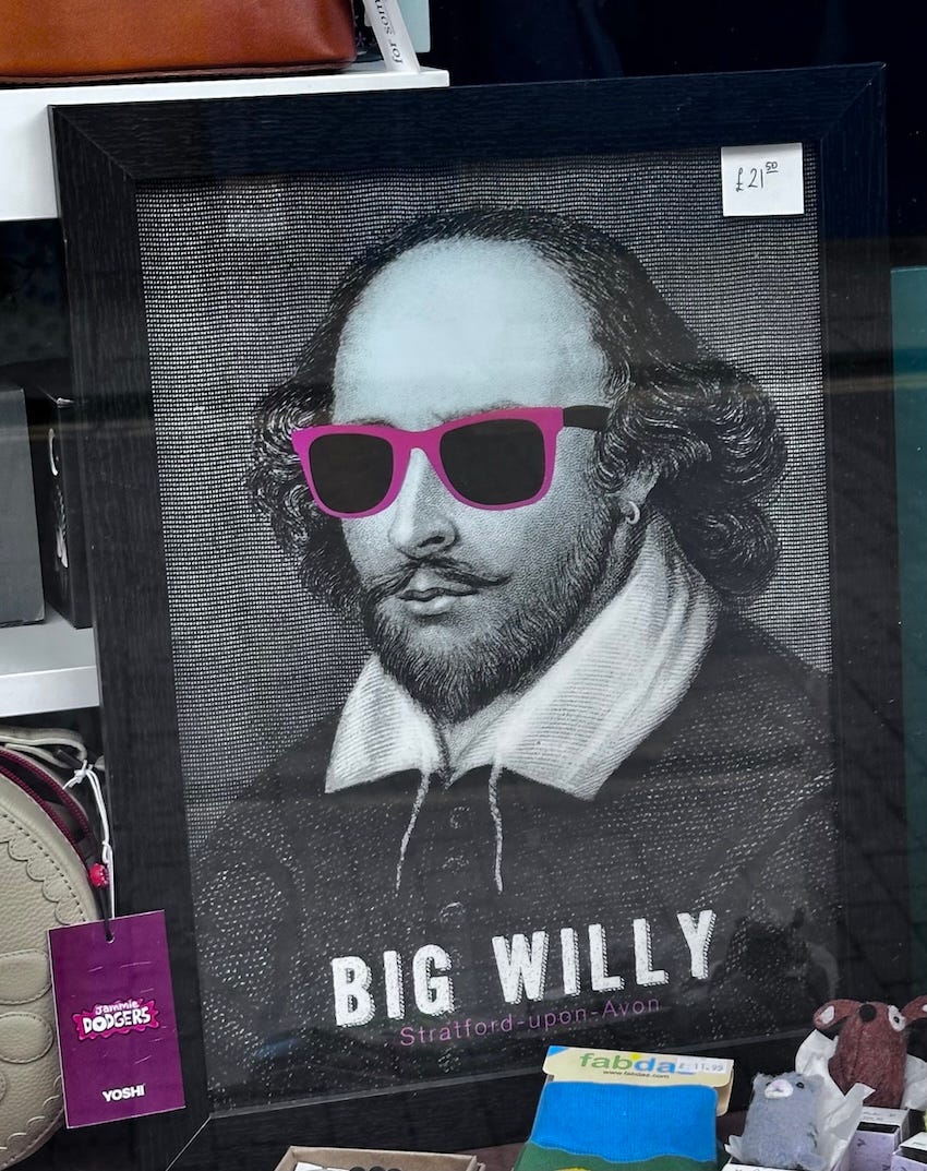 Photograph of items on display in a shop window. Central is a framed image of Shakespeare wearing sunglasses and captioned 'Big Willy'. 