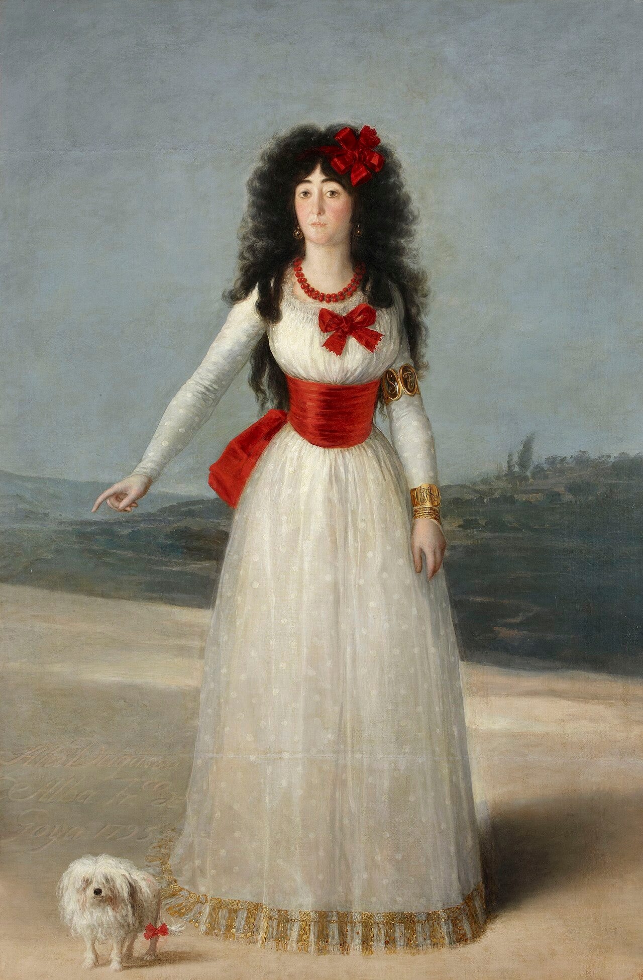 The Duchess of Alba standing in a white dress with red sash pointing at the ground The Duchess of Alba standing in a white dress with red sash pointing at the ground