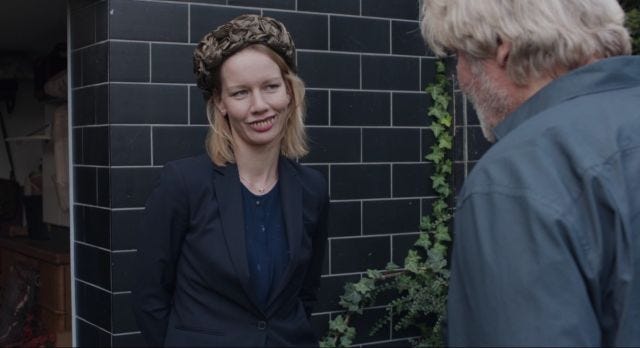 Woman wearing buck teeth and ugly hat smiles at white haired man Woman wearing buck teeth and ugly hat smiles at white haired man