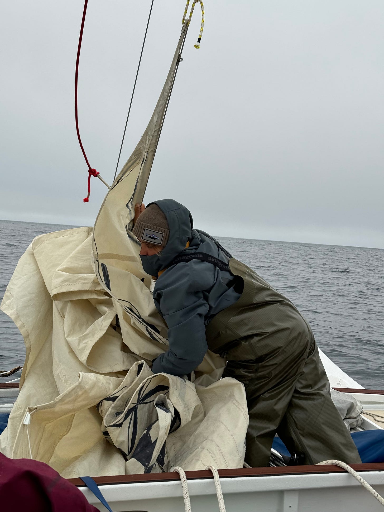 me folding the sails on the sailboat wearing many layers, beanie and my bib