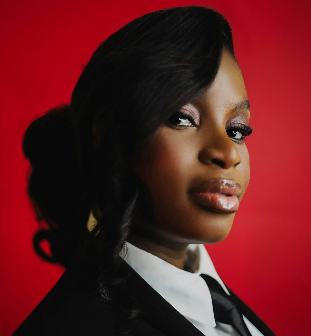 A woman in a suit with a red background.