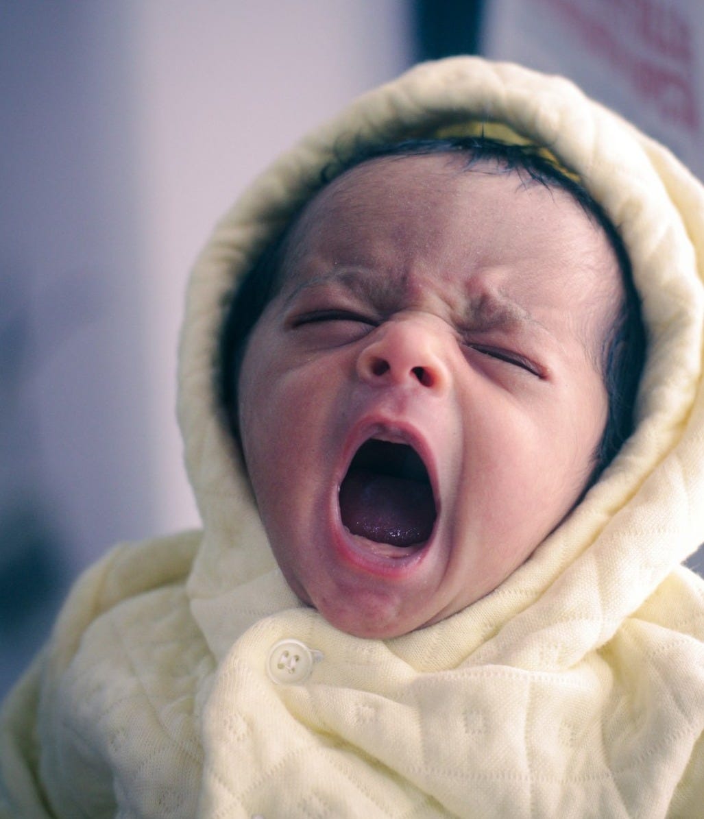 a baby crying with its mouth open