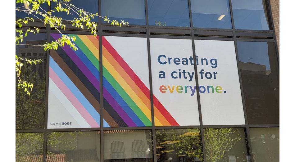 photo of large sign in the windows of Boise City Hall reading 'Creating a city for everyone,' with the final word in rainbow colors. The banner features a diagonal rainbow with the colors of the Pride/Progress flag. 