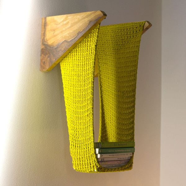 This may contain: a yellow piece of art hanging on the wall next to a pile of books and a wooden object