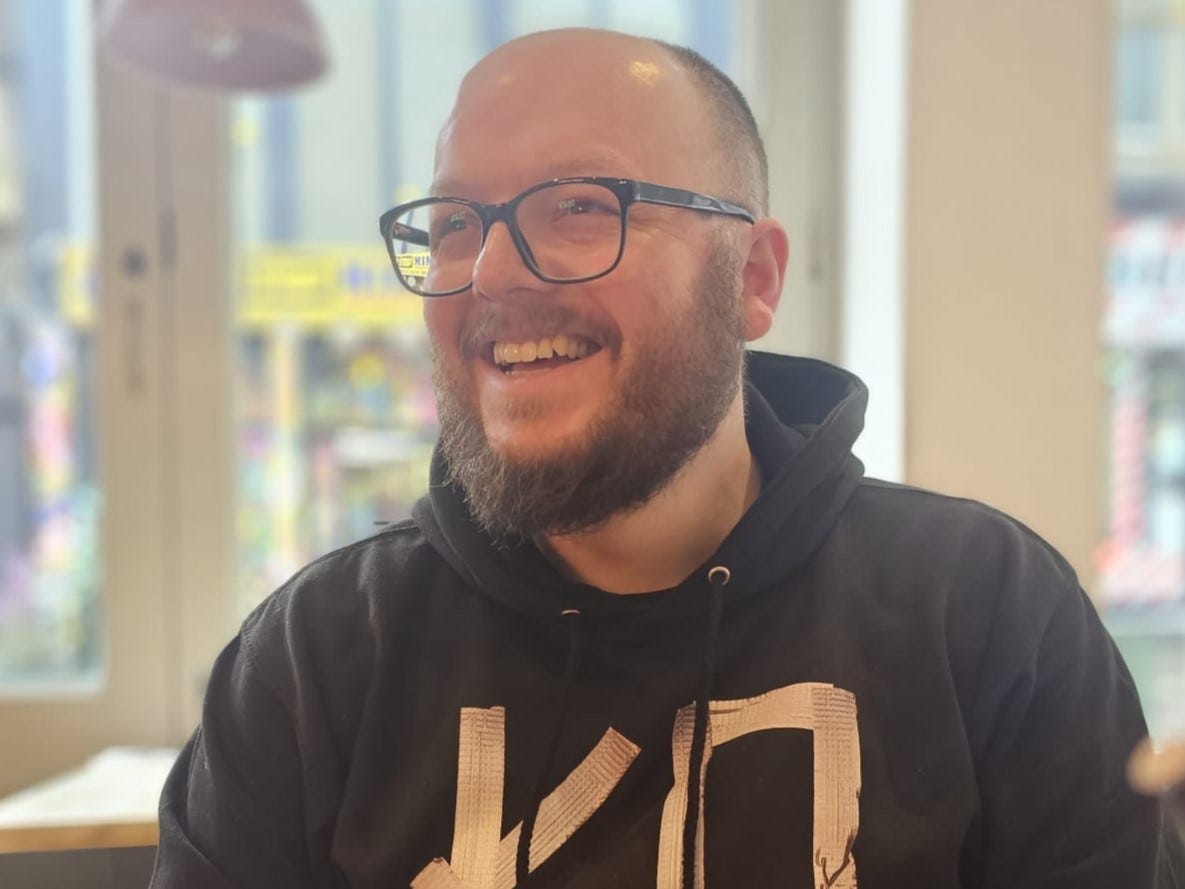 F1 fan Arran Lunt wearing glasses with black frames, laughing during a conversation. F1 fan Arran Lunt wearing glasses with black frames, laughing during a conversation.