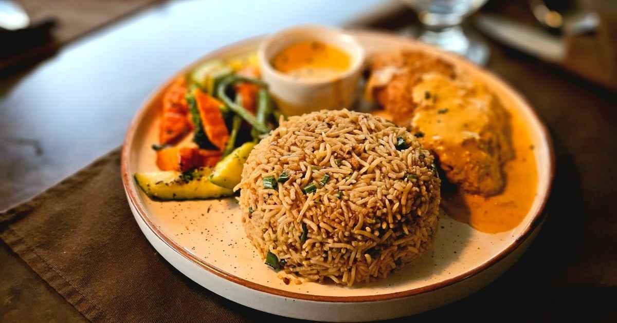 A sumptuous dinner plate featuring seasoned rice, chicken, and colorful vegetables. A sumptuous dinner plate featuring seasoned rice, chicken, and colorful vegetables.