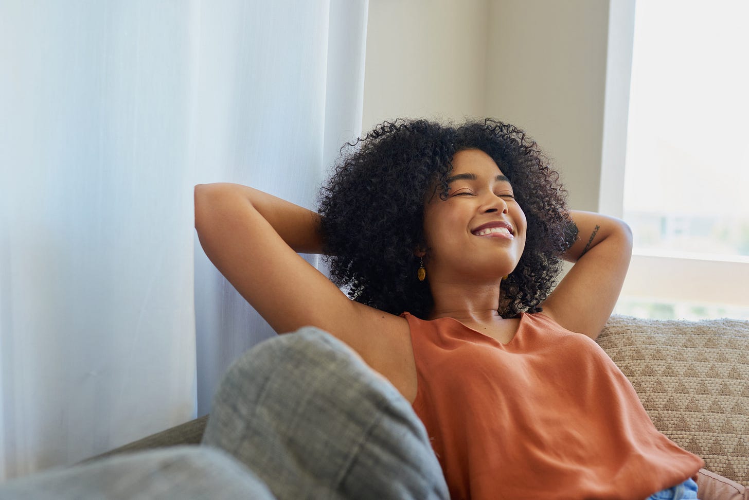 Woman leaning back on a couch smiling confidently Woman leaning back on a couch smiling confidently