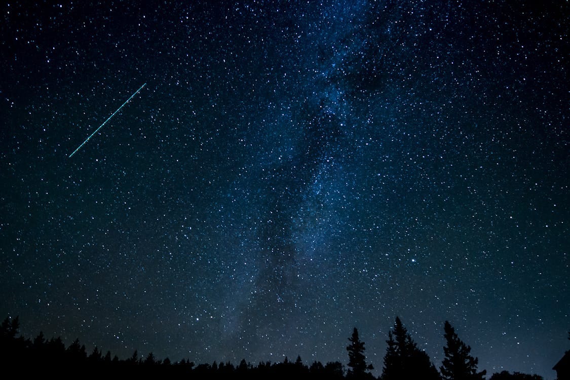 Free A breathtaking view of the starry night sky with a shooting star streaking across the Milky Way. Stock Photo