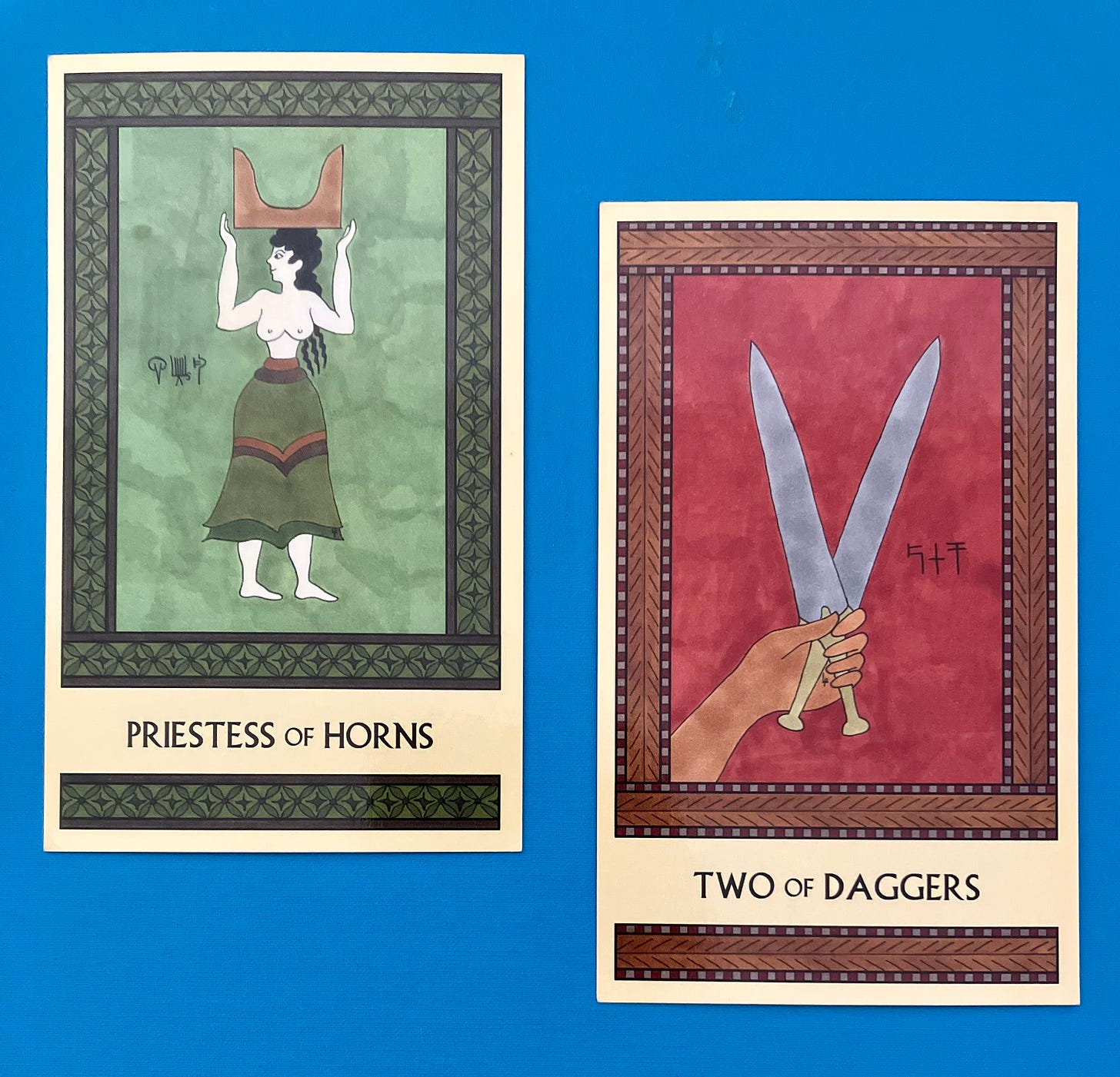 Two Minoan Tarot cards side by side on a deep sky blue background. The Priestess of Horns is painted in shades of green and brown. It shows a Minoan woman standing, her feet facing right but her head turned toward the left, balancing a pair of tan colored sacred horns on her head. The Two of Daggers is painted in shades of deep red and tan. It shows a single hand holding two gold-hilted daggers. 