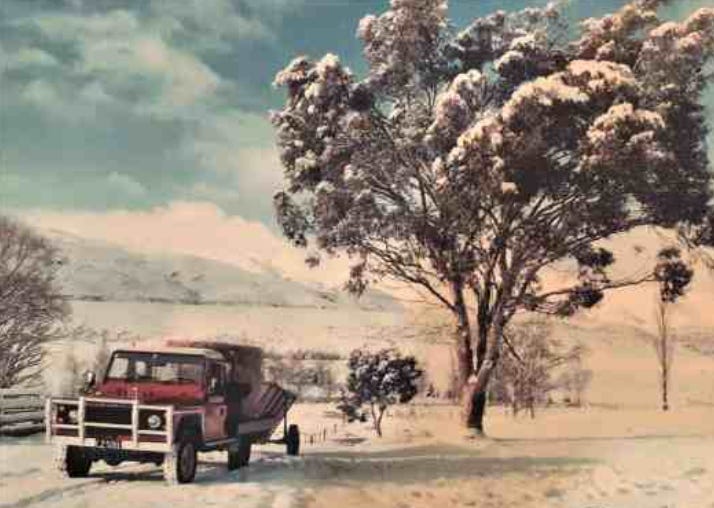 Red 1990s Land Rover in the snow, with round haybale on the back and towing a grain bin Red 1990s Land Rover in the snow, with round haybale on the back and towing a grain bin