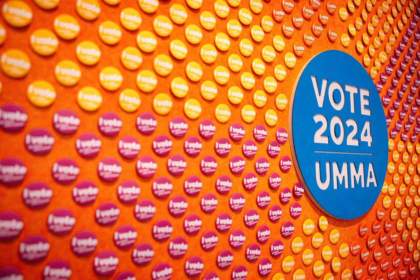 	An array of buttons stuck to the wall create a colorful display at the Ann Arbor County Clerk’s Satellite Office at UMMA.