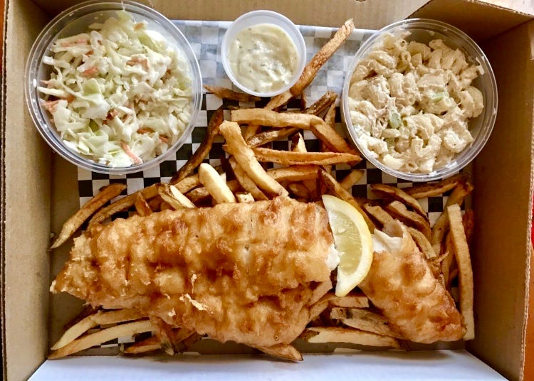 Fish fry over French fries with large sides of coleslaw and tuna mac