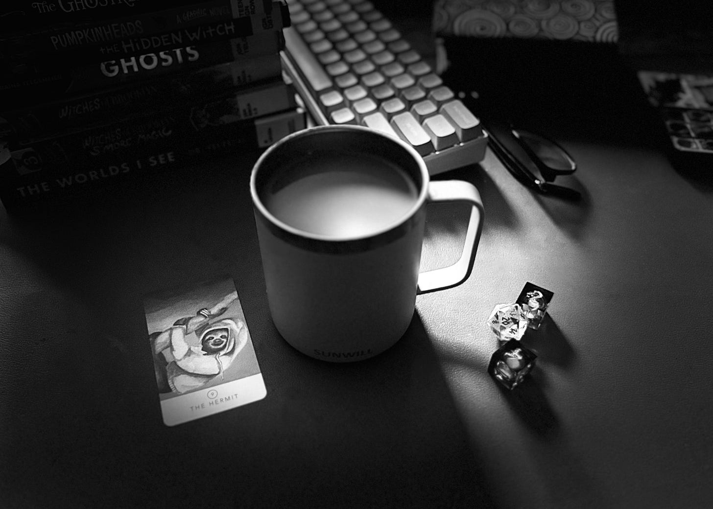 Coffee cup, tarot card, books, dice, and a moody morning