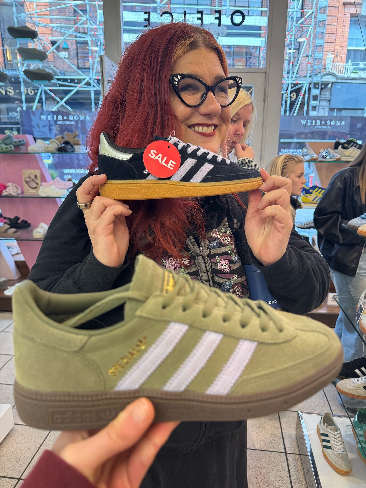The author holding a pair of Adidas and another green Adidas in the foreground. The author holding a pair of Adidas and another green Adidas in the foreground.