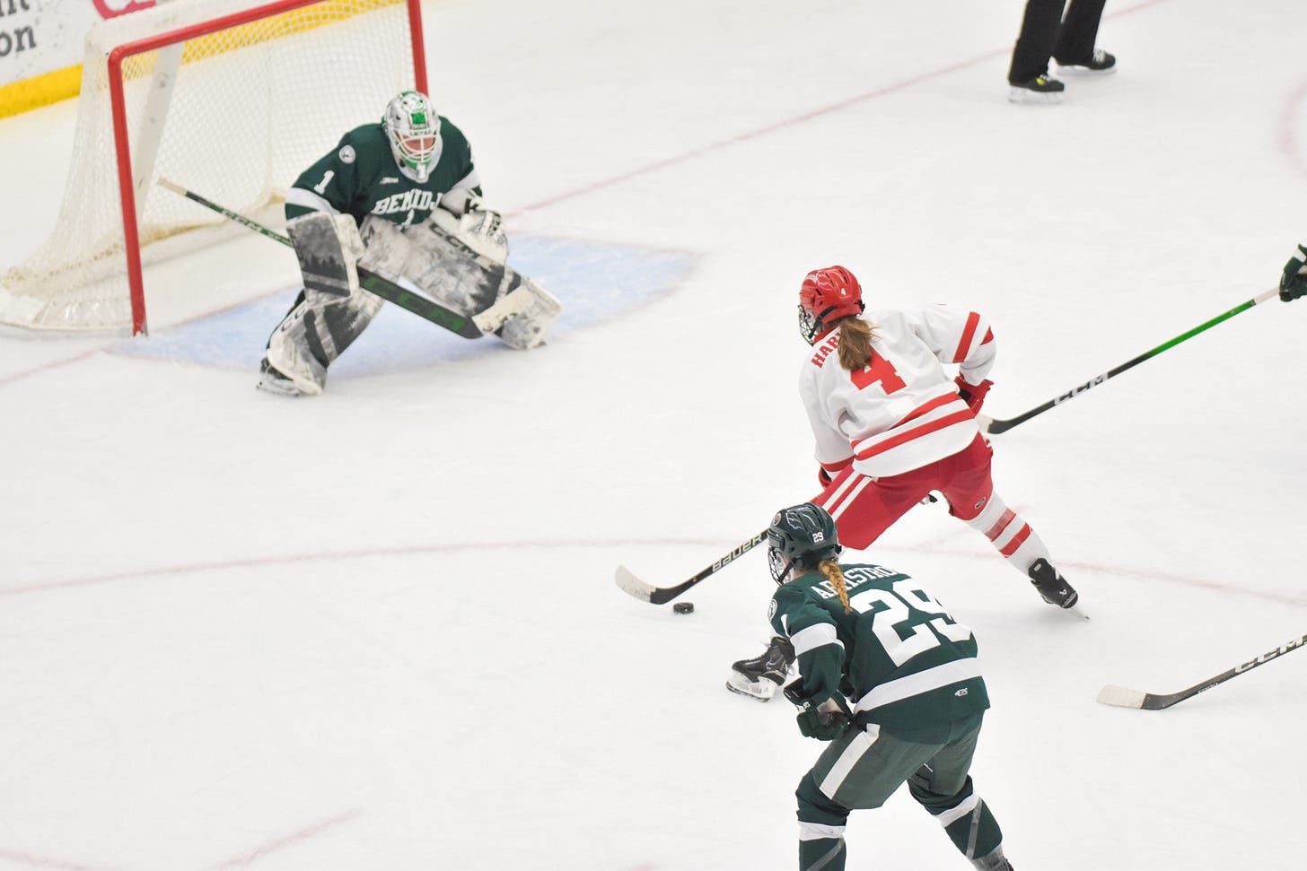 Caroline Harvey alone against Bemidji State women's hockey goaltender Kaitlin Groess. Beavers defenders trail behind Harvey.