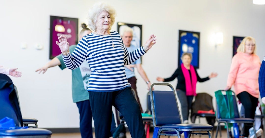 a group of older women dancing in a room a group of older women dancing in a room