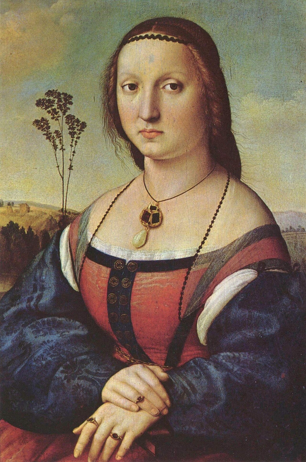 A young woman in a blue and orange dress with a pendant at her neckline, hands folded, in front of a landscape