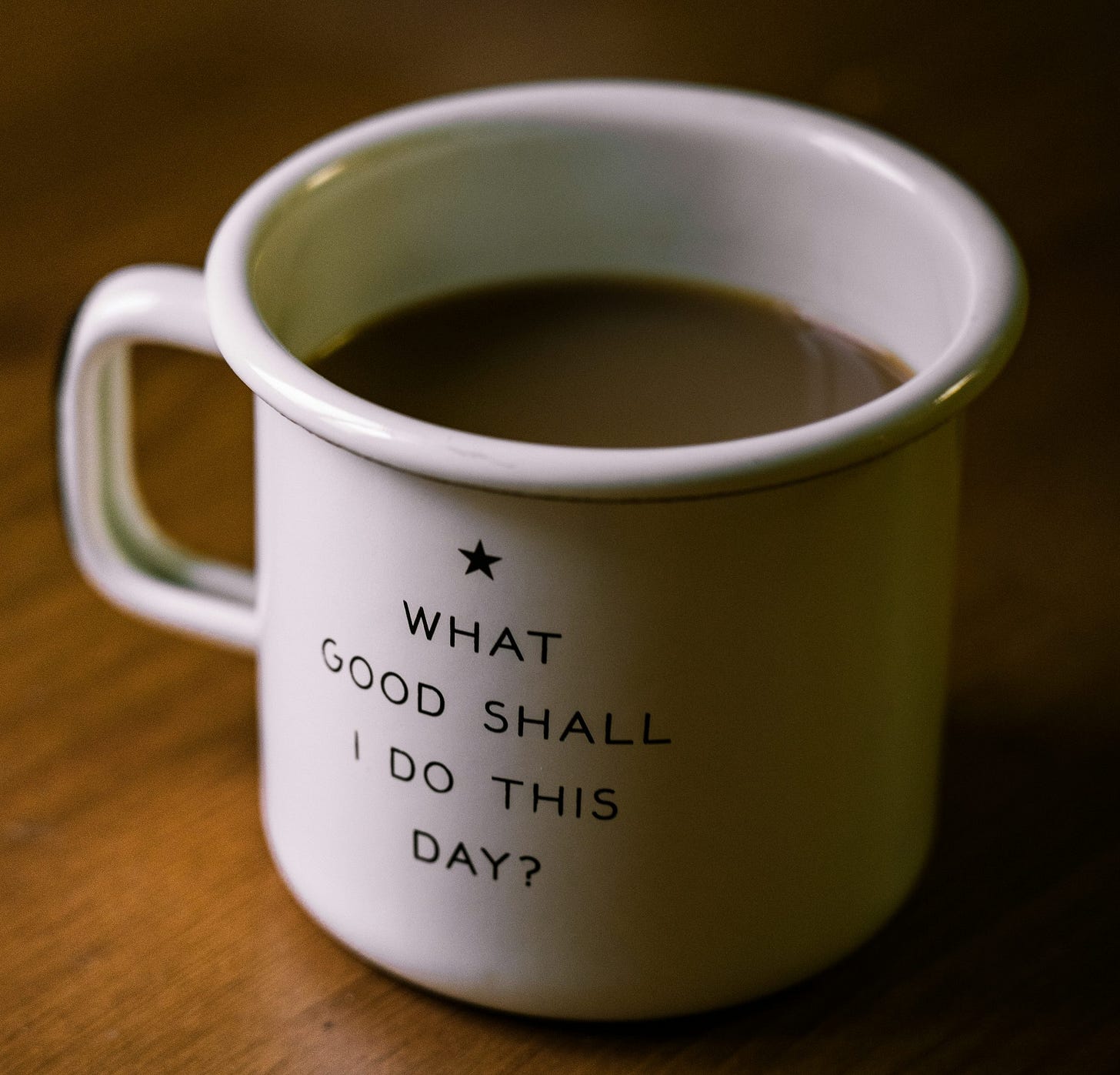 white and black ceramic cup filled with brown liquid on brown wooden sufface