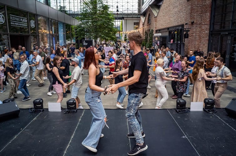 Couple leads a large crowd in a partner dance lesson Couple leads a large crowd in a partner dance lesson