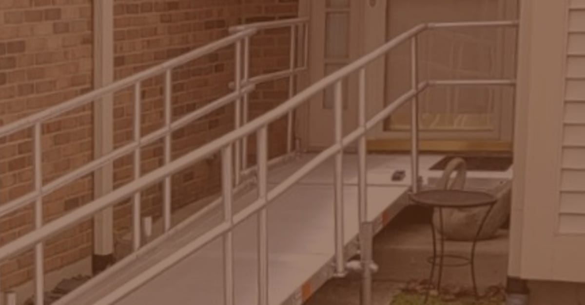 Modest home with narrow wheelchair ramp and old outdoor table nearby