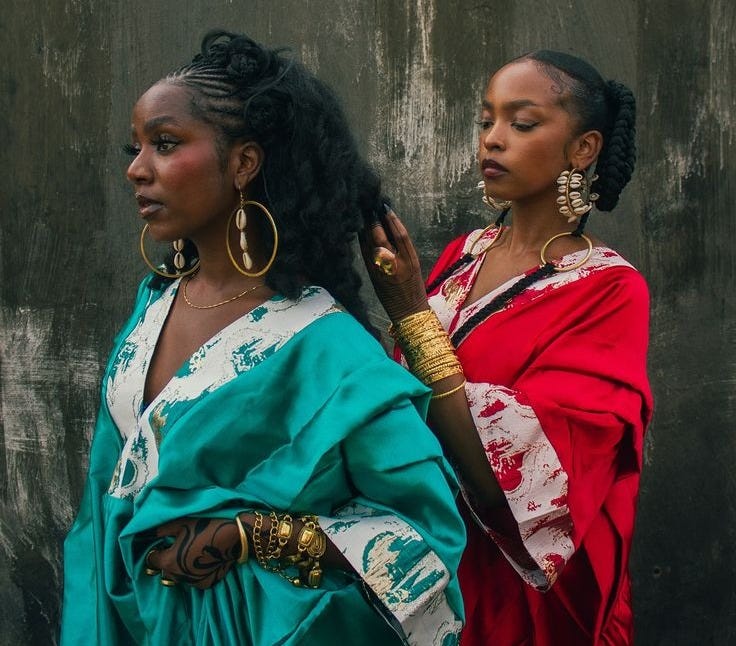 This may contain: two women standing next to each other in front of a wall